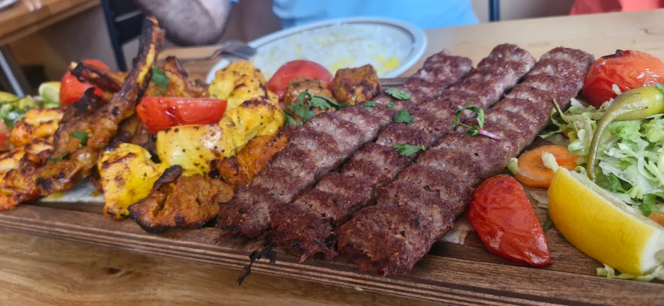 Assorted Persian kebab skewers served on a wooden board at Toranj Restaurant in Edinburgh.